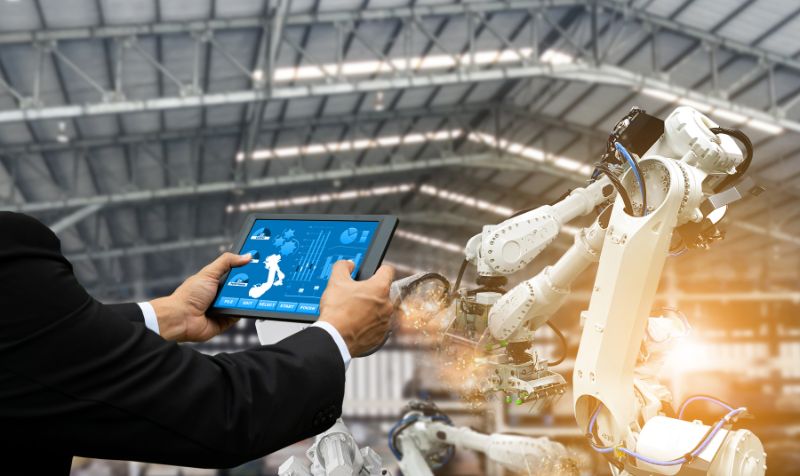 Engineer using a tablet and a heavy automation robot arm in a smart factory industrial. 