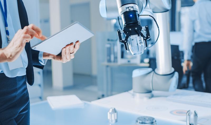 ale Engineer Using Tablet Computer. Interacting with a Robotic Arm Machine, Receiving a Microchip from the Hand. 